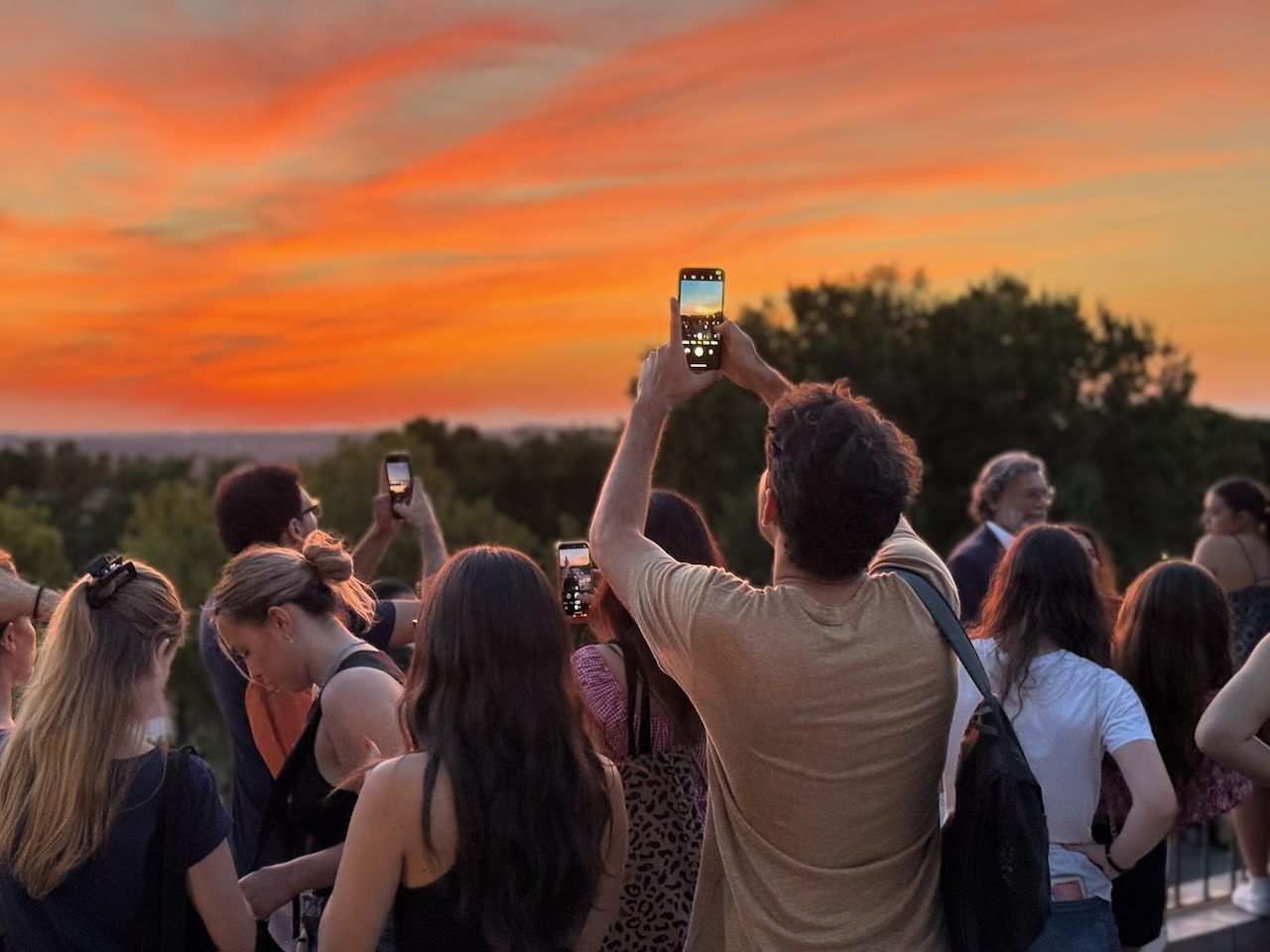 A tourist takes a photo of the sunset on their phone